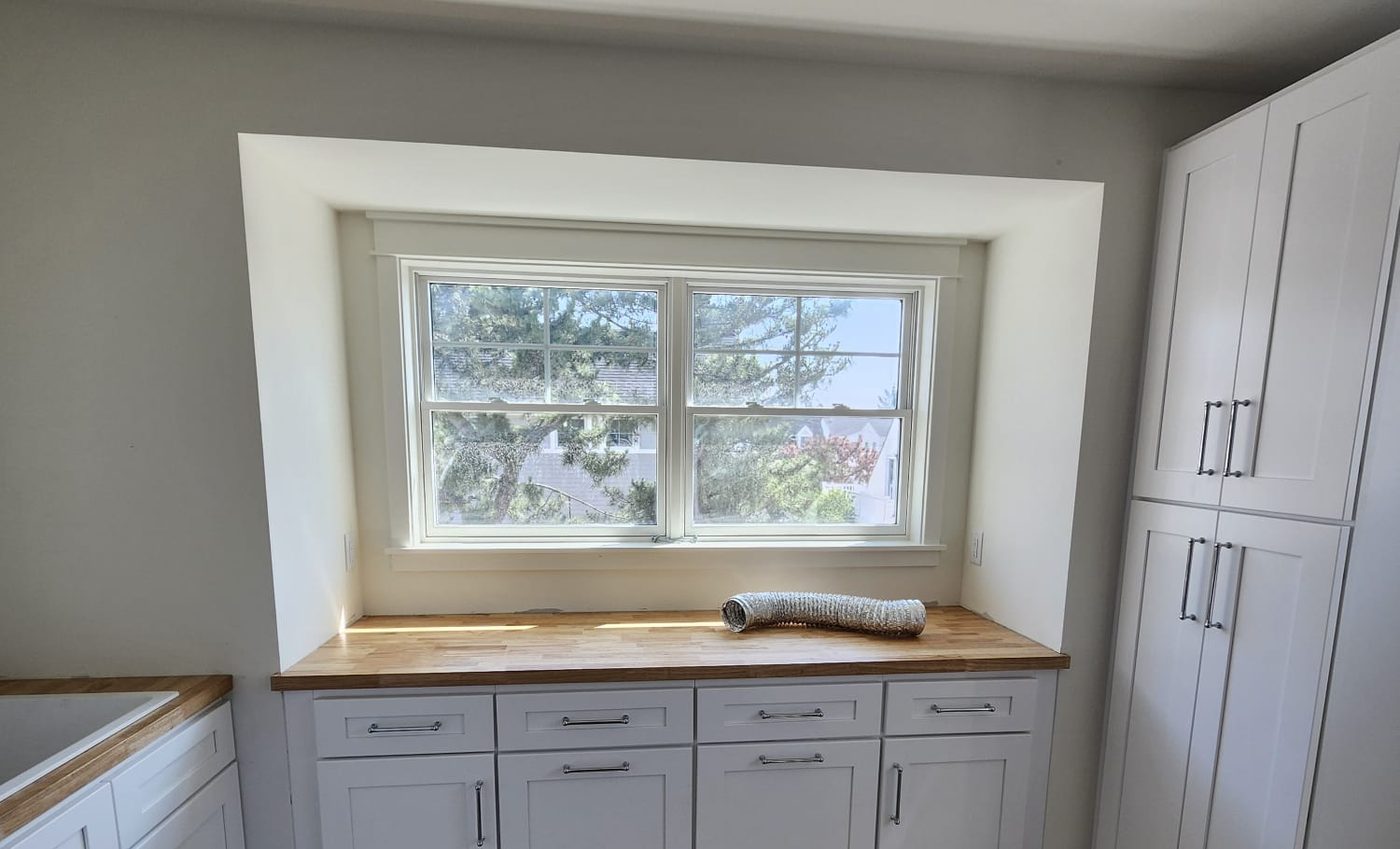 Custom white cabinetry with butcher-block counter and craftsman window trim by FMA Constructions